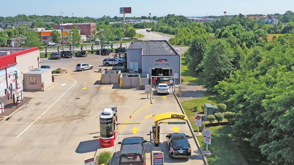 bird eye view of car wash with green trees on the right