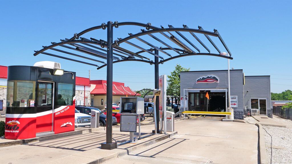 front view of car wash entrance with red booth on left and canopy above